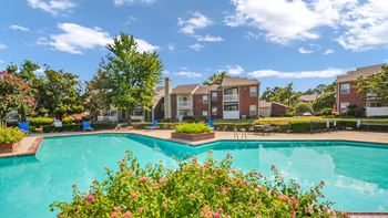 A swimming pool surrounded by flowers and residential buildings.
